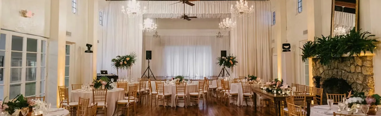 Exterior view of Coral Gables Country Club with palm trees, a golf course, and a clubhouse