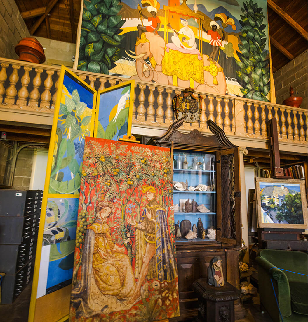 Artist studio at Bonnet House with a large easel painting, folk-art mural, seashell cabinet, and vaulted wooden ceiling