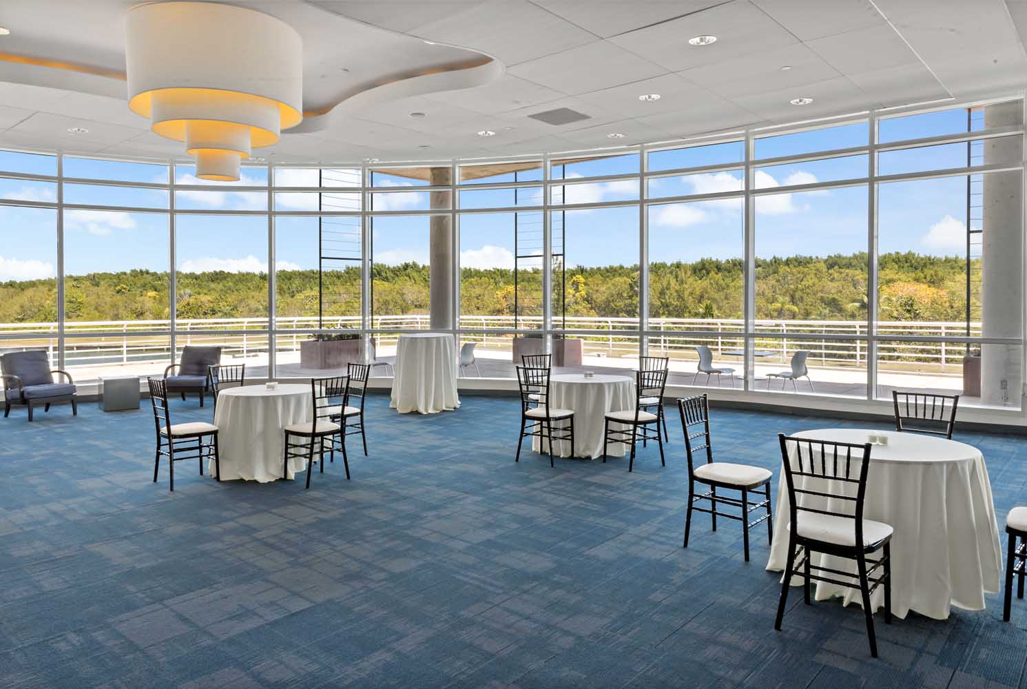 Spacious ballroom at Palmetto Bay Village Center with curved windows, elegant seating, and natural light throughout