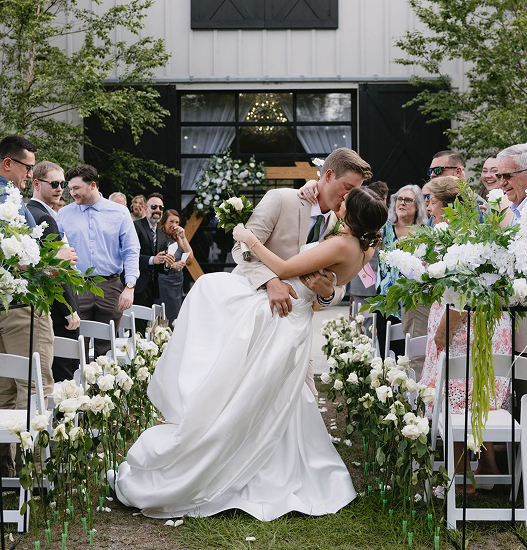 Joyful couple celebrating their wedding at Trellis 925, surrounded by guests, soft lighting, and rustic brick wall