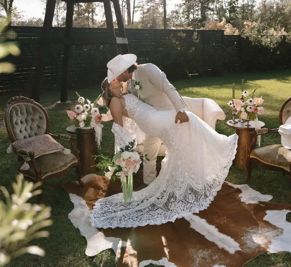 Indoor wedding reception at Trellis 925 with a long table adorned with roses and round tables in the background