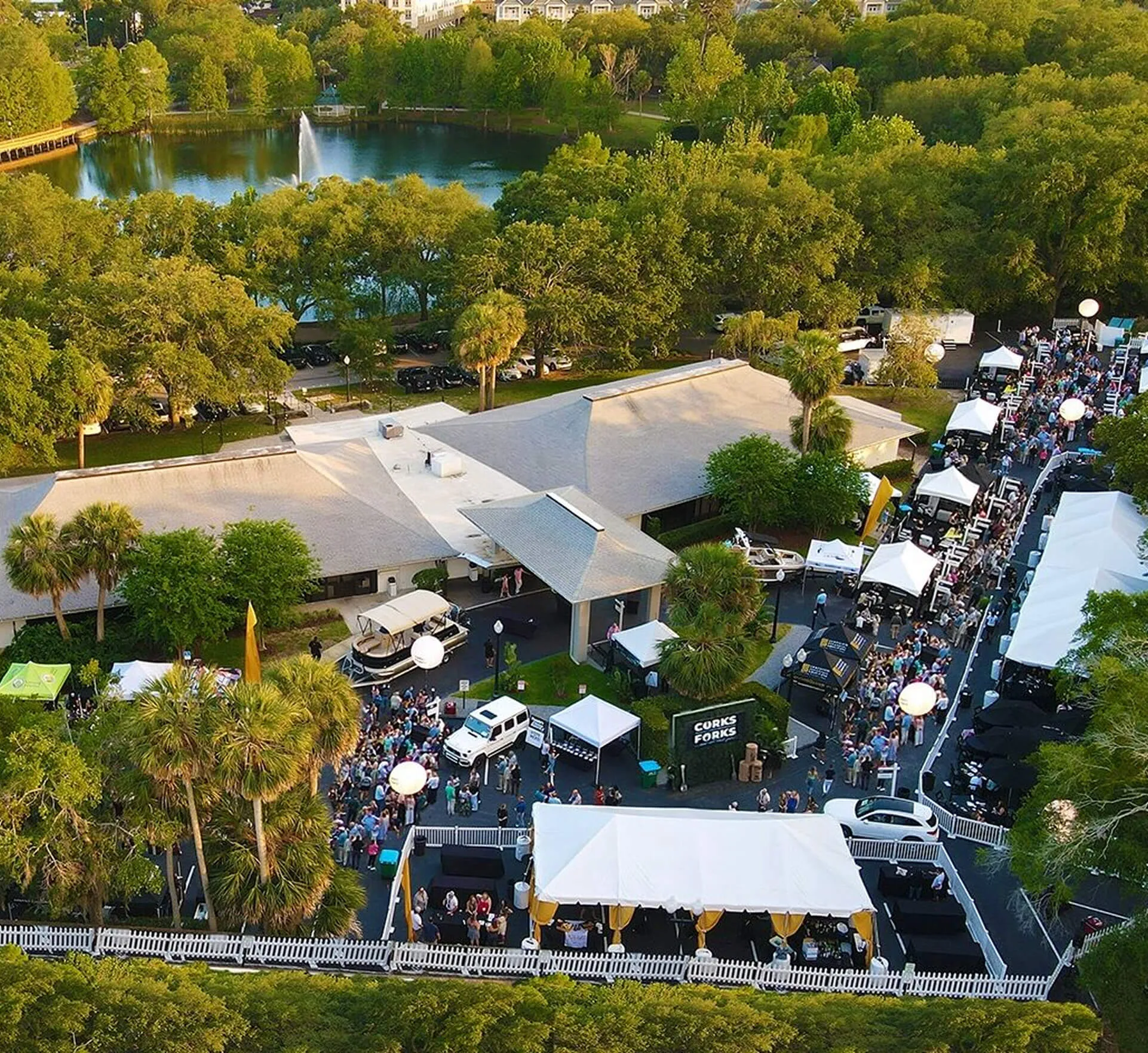Aerial view of an outdoor festival at Venue on Lake Lily in Maitland with vendor tents, guests, and Lake Lily with its fountain in the background