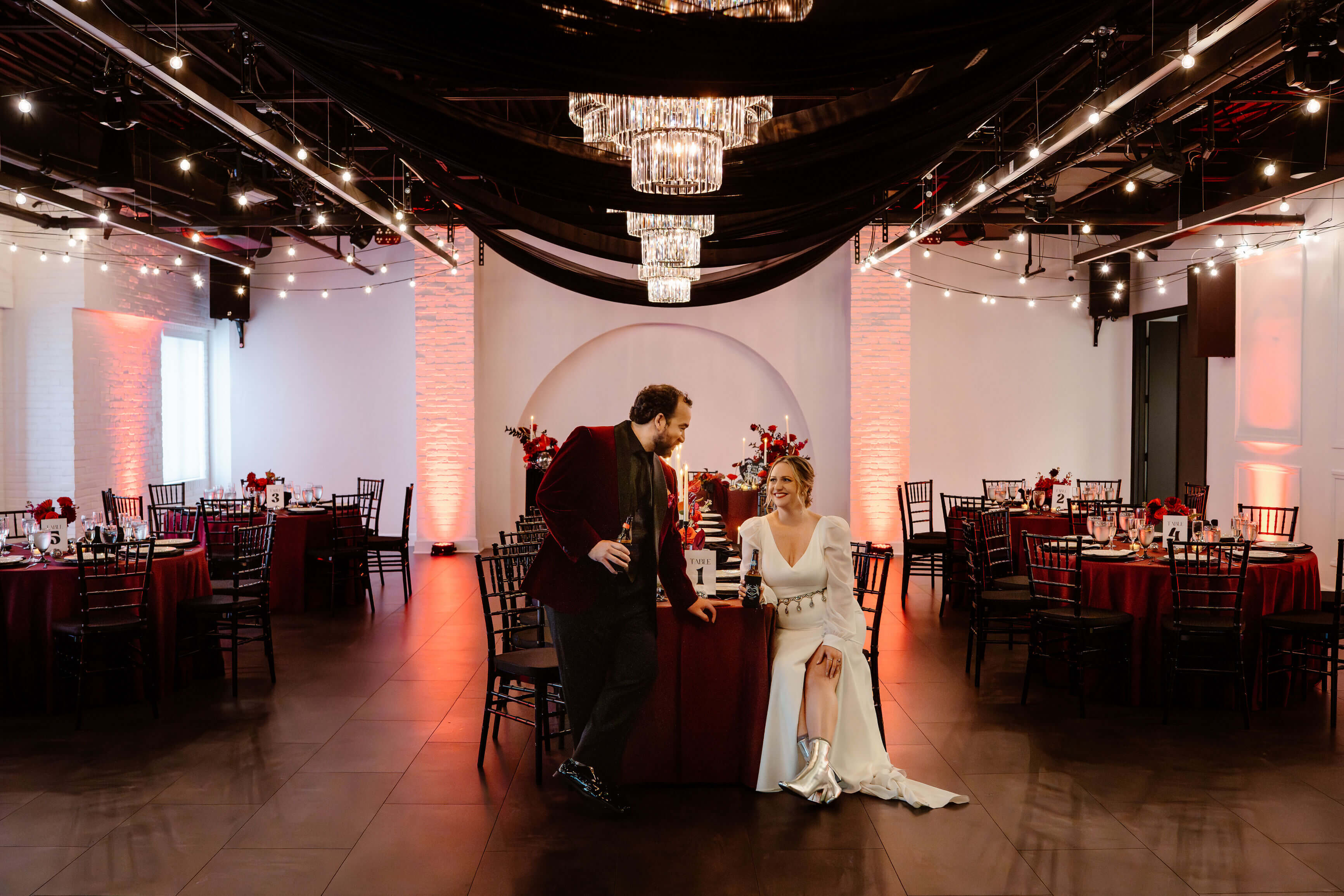 Joyful couple celebrating their wedding at Trellis 925, surrounded by guests, soft lighting, and rustic brick wall