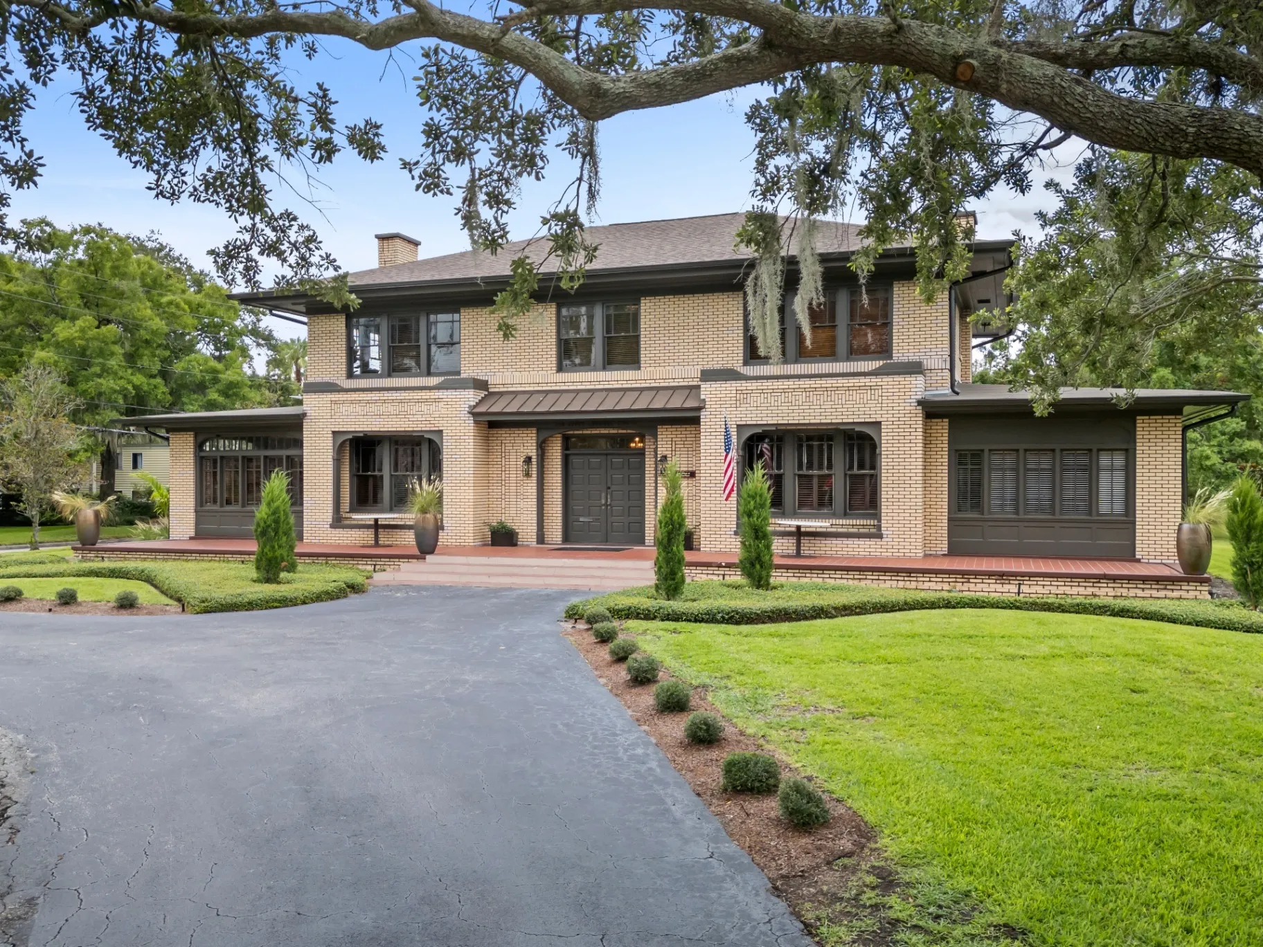 Historic yellow brick mansion at The Woodruff on Lake Lucerne with a wide green lawn in downtown Orlando