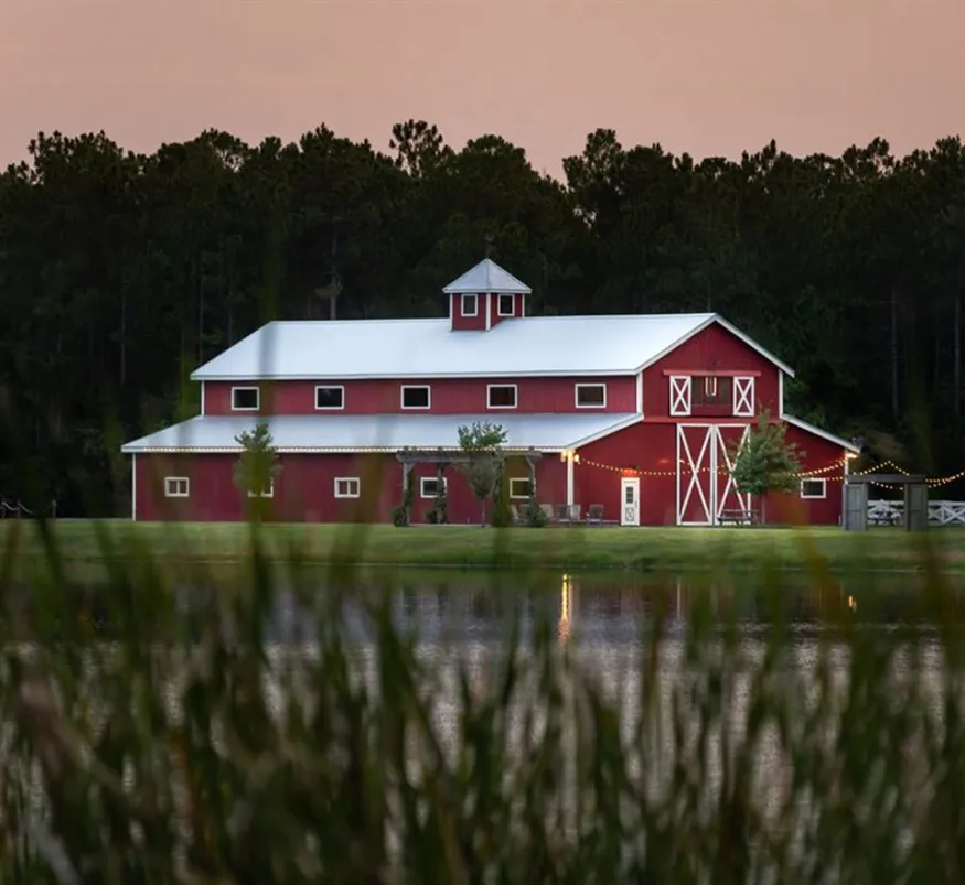 Interior view of Tringali Barn showing rustic wooden beams, elegant chandeliers, and spacious event space