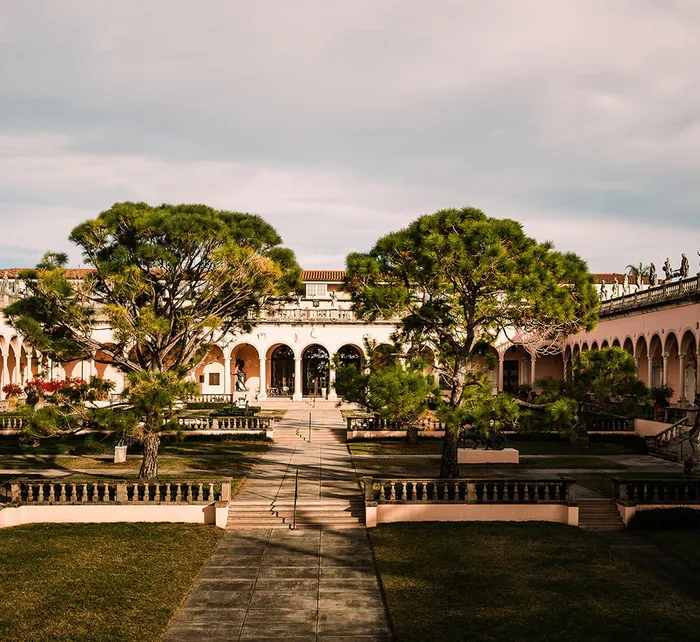 Elegant outdoor wedding setup at The John and Mable Ringling Museum of Art courtyard with statue, palm trees, and dinner tables