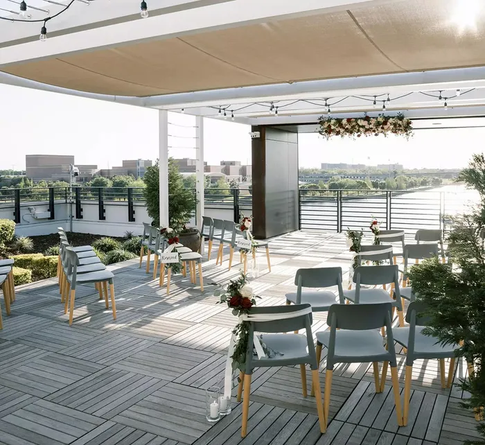 Couple exchanging vows at Rooftop 220 with guests seated in front and scenic river view in the background