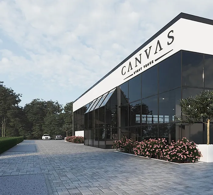 Exterior view of Canvas Event Venue at sunset with modern glass design, warm lighting, and palm trees in the foreground