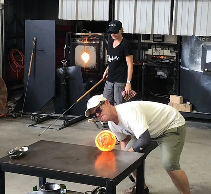Colorful hand-blown glass art displayed on tables inside Morean Glass Studio & Hotshop, a modern artisan gallery and gift shop